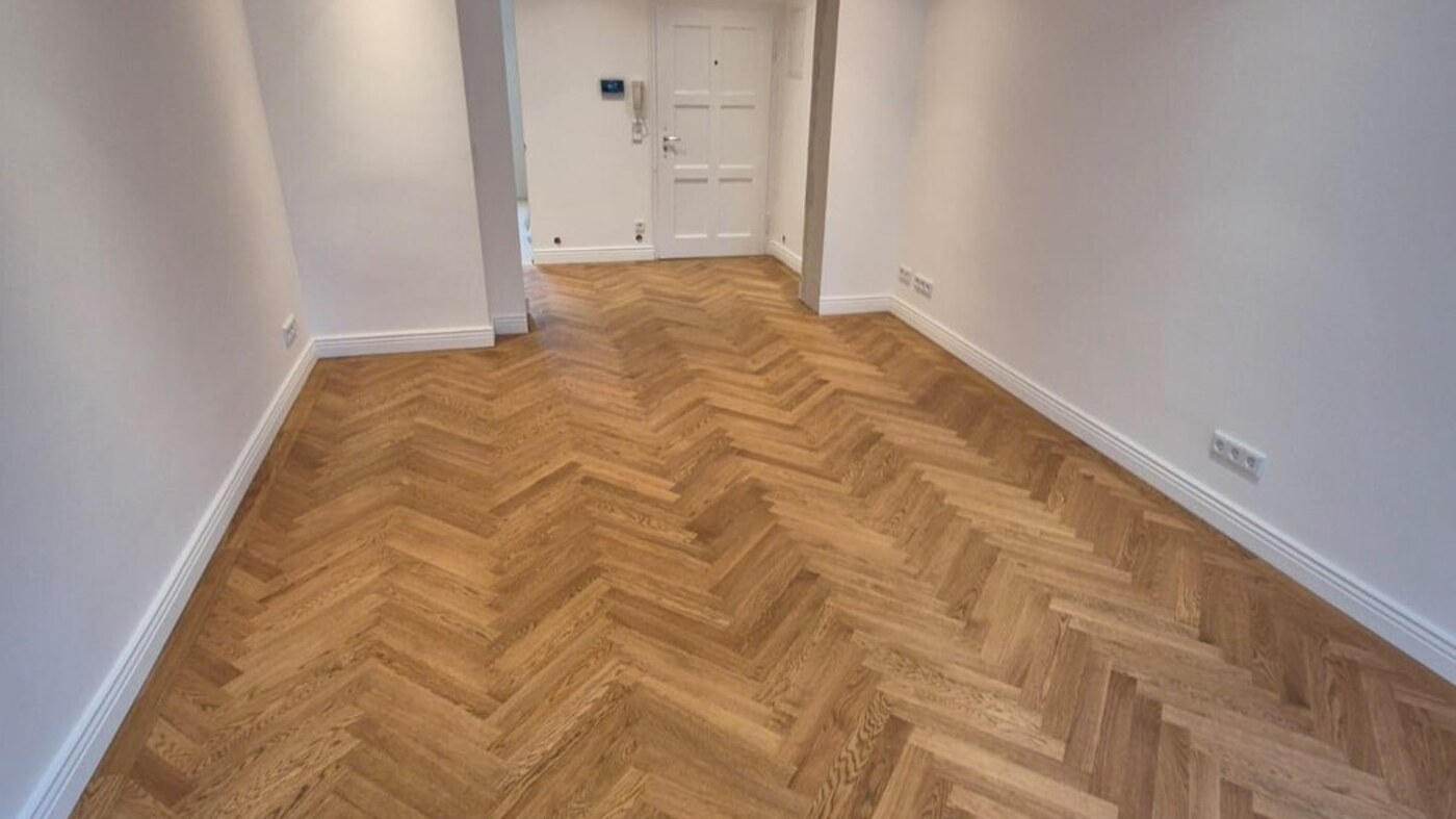 Münchner Altbau-Flur mit drei sage-grünen Türen, Eichenholzparkett und einfallendem Tageslicht