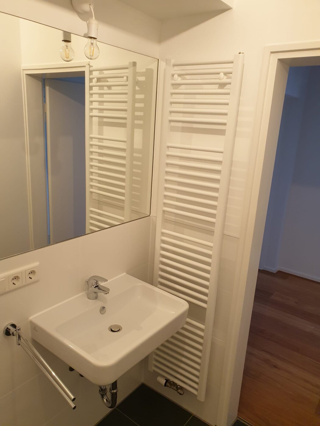 Modernes Badezimmer mit Waschtisch, Spiegel und Handtuchheizung
