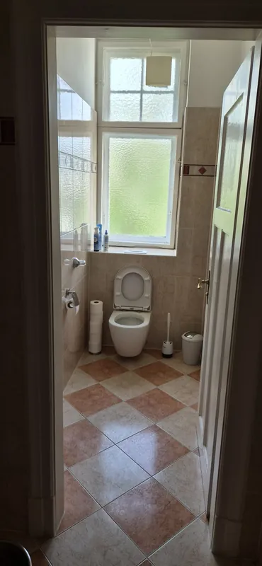 Vorher: altes WC unter dem Fenster, beige Fliesen mit Bordüre